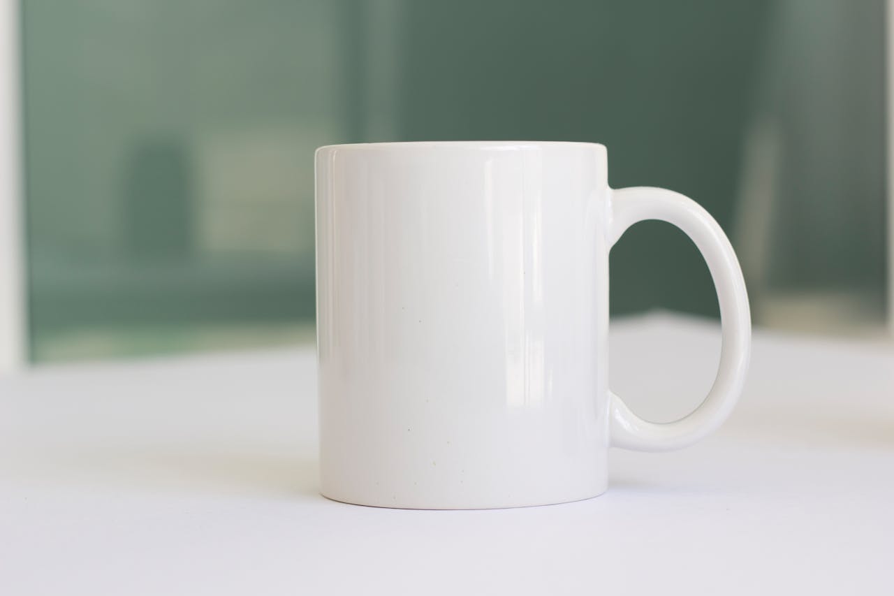 A simple white ceramic mug placed on a tabletop, perfect for product mockups.