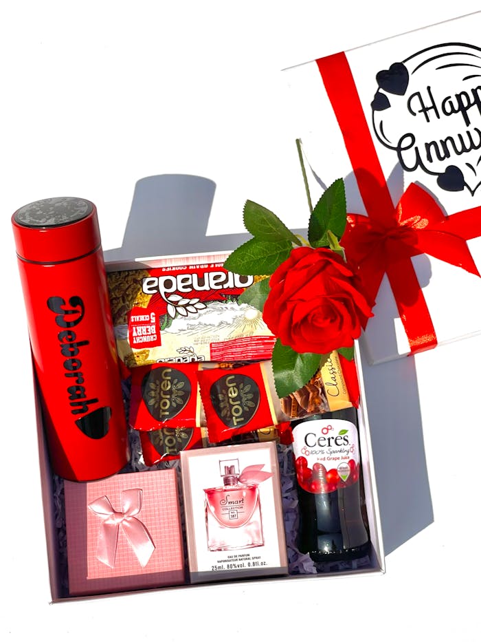 Elegant anniversary gift box with red-themed items and a rose. Perfect romantic gesture.